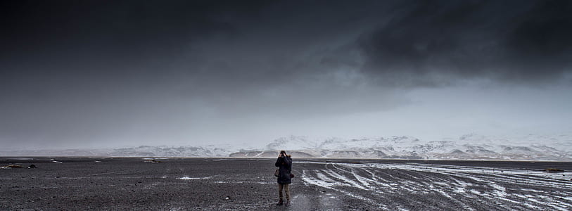 Man Standing on Gray Dessert Under Gray Cloudy Sky during Daytime thumbnail