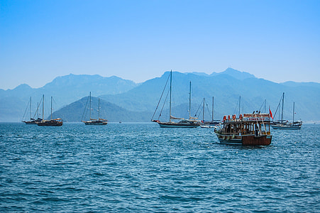 boats in the sea with mountain in the background during day thumbnail