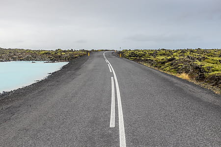 asphalt road between green grass fields thumbnail