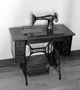 grayscale photo of Singer treadle sewing machine near concrete wall thumbnail
