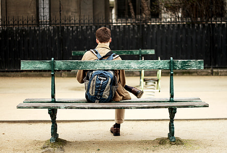 man sitting on green wooden bench thumbnail