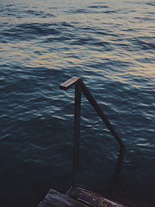black metal railing with brown wooden stairs on body of water at daytime thumbnail