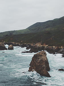 rock formations on body of water under cloudy sky at daytime thumbnail