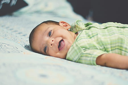toddler in green plaid shirt lying on blue surface thumbnail