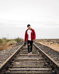man walks on brown train rail during daytime thumbnail