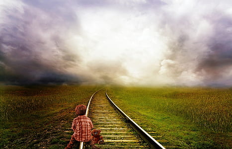 boy sitting on train rail under cloudy sky thumbnail