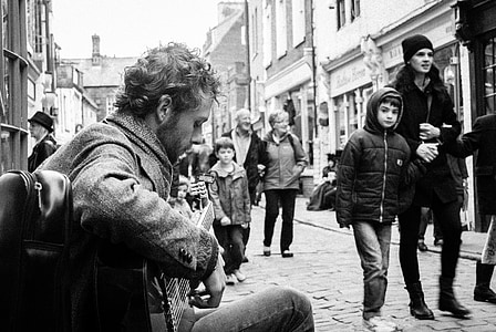 grayscale photo of man playing guitar on street thumbnail