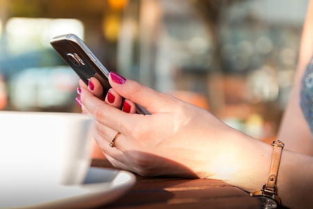 Person Holding a Black Smartphone Wearing a Brown Leather Strap Watch thumbnail
