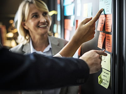 smiling woman looking at sticky notes on black board thumbnail