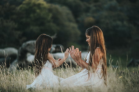 two girls playing at brown leafed grasses thumbnail