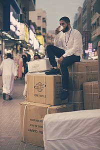 man sitting on boxes drinking on white cup during daytime thumbnail