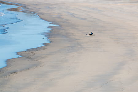 person sitting on seashore during daytime thumbnail