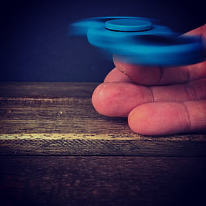 person playing with blue fidget spinner thumbnail