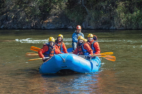 four smiling people wearing life vest riding on inflatable boat during daytime thumbnail