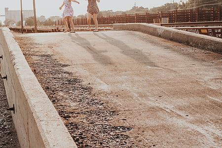 two women standing on gray concrete road during daytime thumbnail
