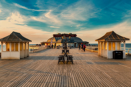 black metal benches in the middle of brown wooden surface between white wooden sheds at daytime thumbnail