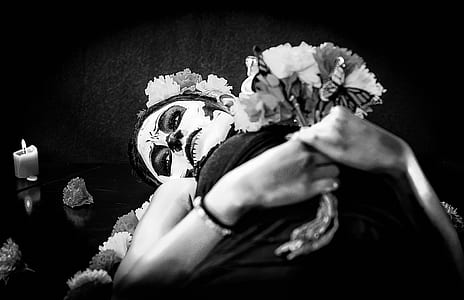 grayscale photo of woman lying while holding flowers thumbnail