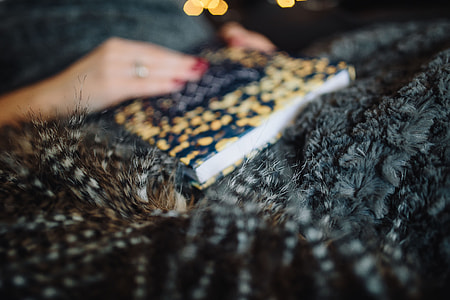 Young woman at home reading Hygge book and drinking thumbnail