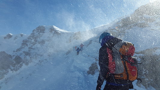 man carrying backpack near mountain during winter season thumbnail
