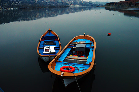 two blue-and-brown rowboats on body of water thumbnail