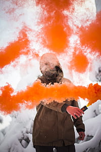 person holding orange smoke during daytime thumbnail