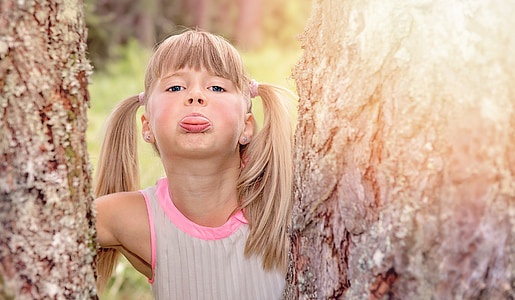 girl in between of tree near forest during daytime thumbnail