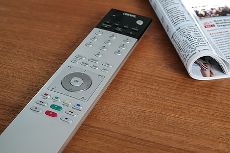 black and gray remote controller on table beside opened book thumbnail