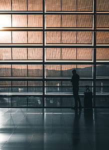 silhouette photo of man standing beside luggage thumbnail