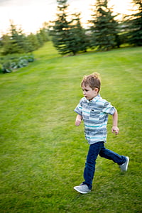 boy walking on lawn field during daytime thumbnail