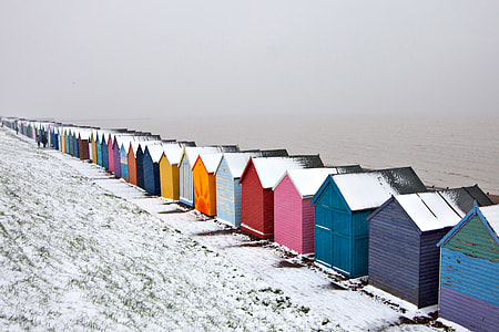 Winter-time snow covered scene of some beach huts on the Kent Coast in England thumbnail