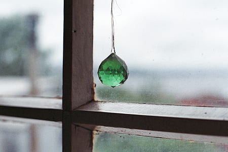 green gemstone hanging on clear glass window thumbnail