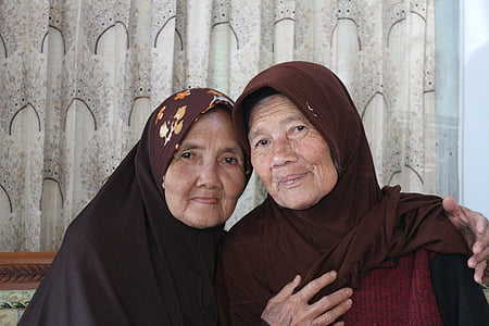 two woman sitting wearing hijabs thumbnail