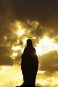 silhouette of Mother Mary statue under cloudy sky thumbnail