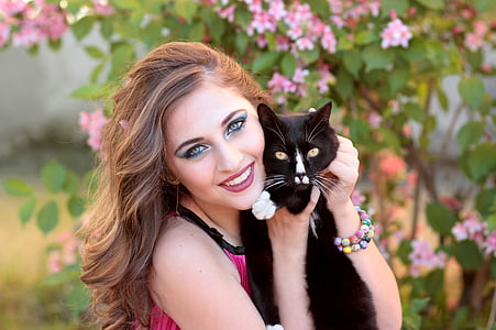 woman wearing pink top holding black cat thumbnail