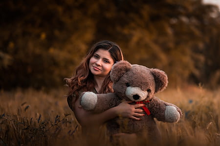 woman holding bear plush toy on grass field thumbnail