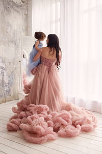 photo of woman in brown floral dress carrying girl in blue dress thumbnail