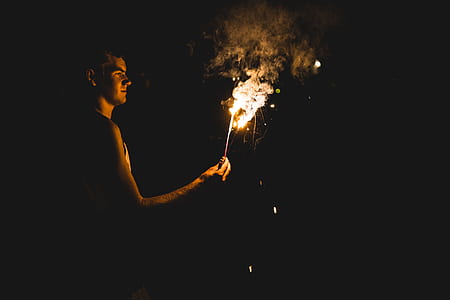 person holding lighted sparkler during nighttime thumbnail