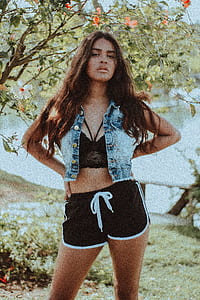 woman in black crop-top and dolphin shorts standing near plant thumbnail