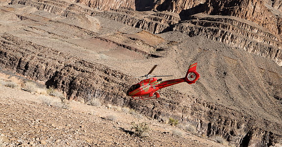 red RC helicopter flying over mountain thumbnail