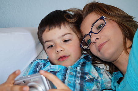 boy holding gray compact camera beside woman wearing black framed eyeglasses thumbnail