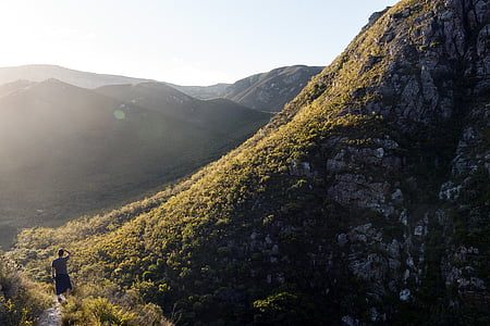 person walking on pathway near mountain during daytime thumbnail