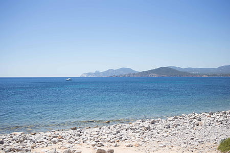 A stony seashore in sunlight with horizon in the background thumbnail