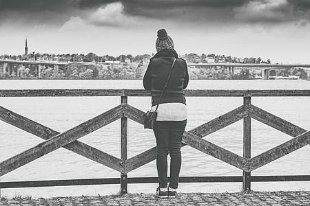 gray scale of woman standing near fence thumbnail