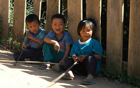 three children sitting on ground during daytime thumbnail