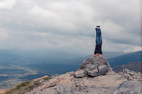 person wearing black and blue suit on gray rock near cliff thumbnail