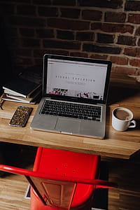 Creatives desk with laptop, camera, journals and books in front of brick wall thumbnail