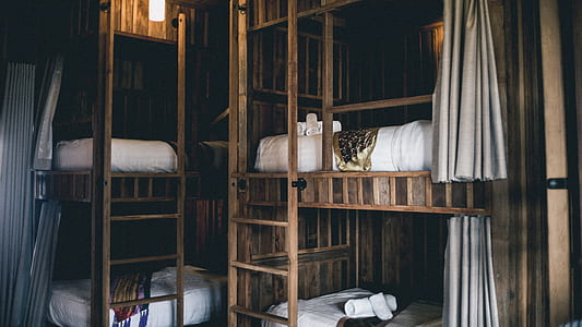 brown wooden bunk bed with white beds near black wall thumbnail