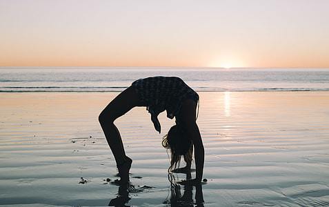 woman bending her body on seashore during golden hour thumbnail