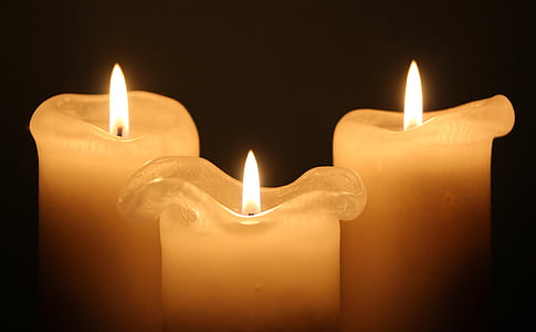three white lighted pillar candles thumbnail