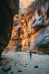 woman stands on river beside rocks under mountain during daytime thumbnail